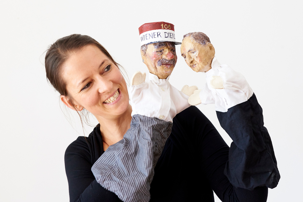 Frau mit zwei Handpuppen lächelt in die Kamera
