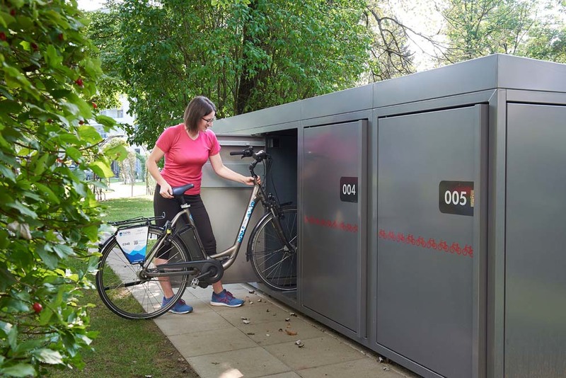 Frau mit Rad bei der Fahrradbox