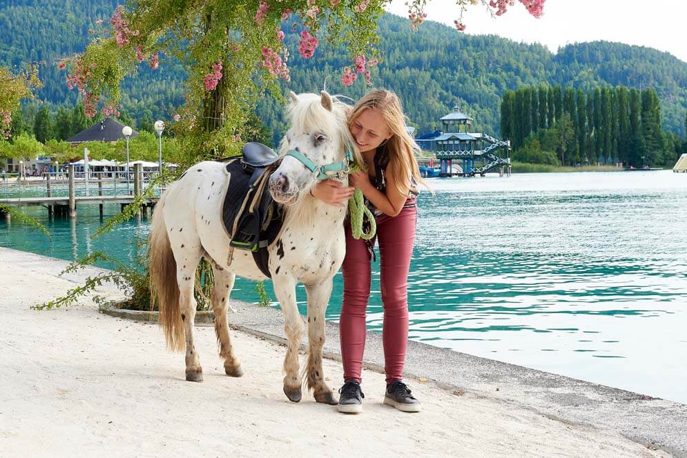 Pony mit Maedchen an der Promenade