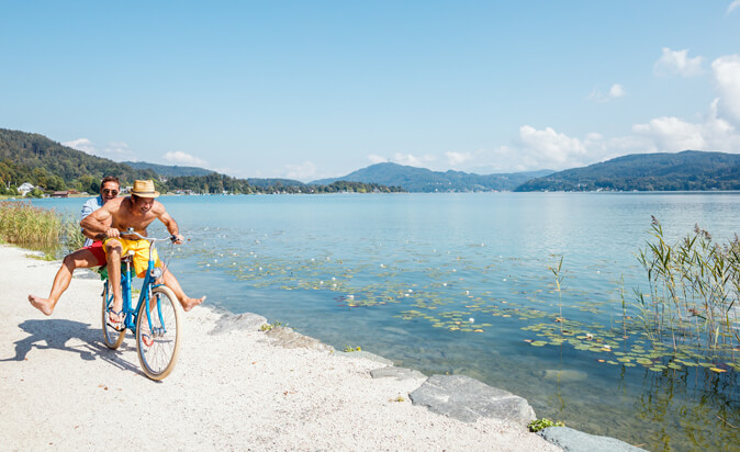 Zwei Männer fahren mit dem Fahrrad dem See entlang