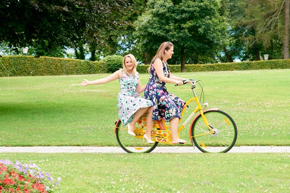 2 Frauen sitzen auf einem Rad und fahren durch den Hotelpark