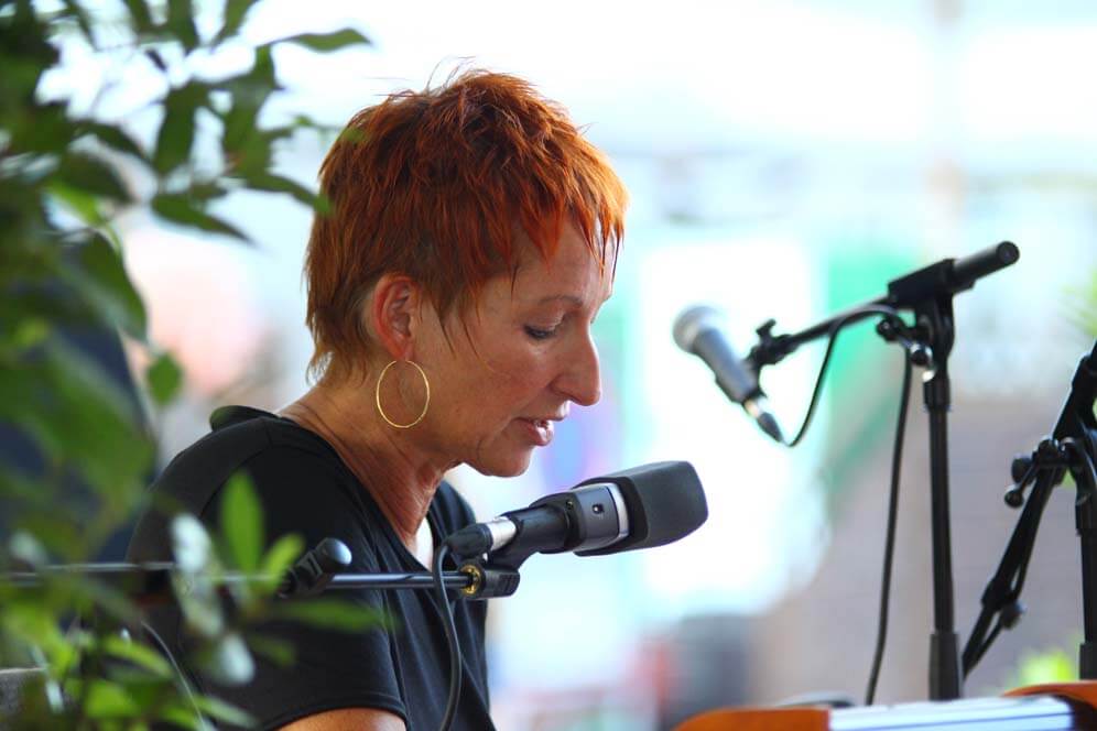 Eva Rossmann mit Mikrofon an einem Tisch
